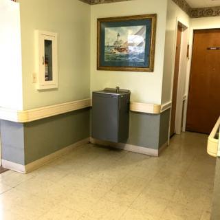 A quiet hallway featuring a water cooler and a framed artwork.