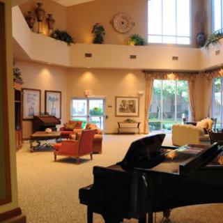 A spacious and elegantly decorated living room with a grand piano and large windows.