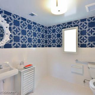 A stylish bathroom with blue patterned wallpaper and modern fixtures.