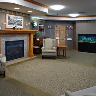 A cozy living room featuring a fireplace, an armchair, and an aquarium.