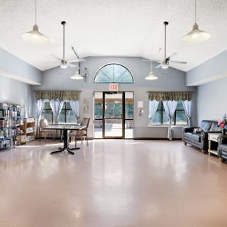 A spacious and bright lounge area featuring comfortable seating, tables, and large windows for natural light.