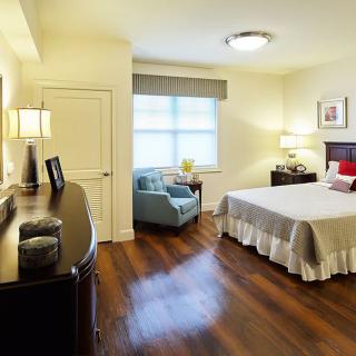 A cozy and well-lit bedroom featuring a large bed with crisp linens, wooden floors, and stylish decor.