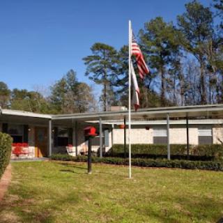 A peaceful residential scene featuring a house with well-maintained landscaping, an American flag flying, and a mailbox.