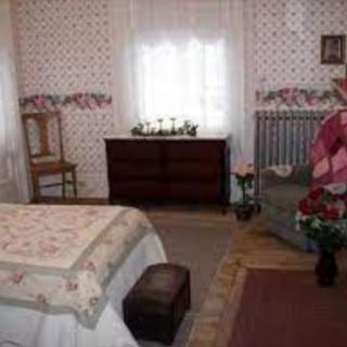 A cozy bedroom with floral wallpaper, a bed, a dresser, and a chair.