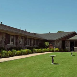 A single-story house with a well-maintained lawn under a clear blue sky.