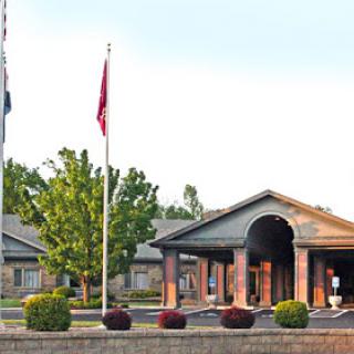 A welcoming entrance to a building, featuring flags and well-maintained landscaping.