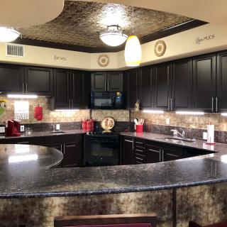 A modern kitchen with dark cabinets and granite countertops, featuring stylish pendant lighting and a decorative backsplash.