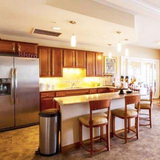 A modern kitchen with wooden cabinets, stainless steel appliances, and bar seating.