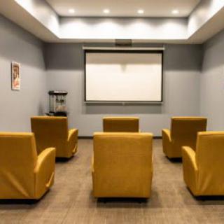 A cozy home theater setup with yellow armchairs and a projector screen.