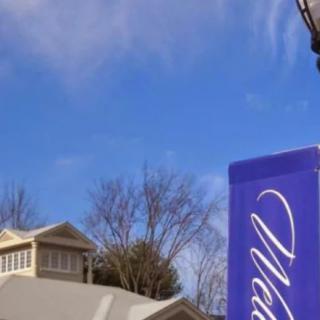 An outdoor sign stands in front of a building with a clear blue sky in the background.