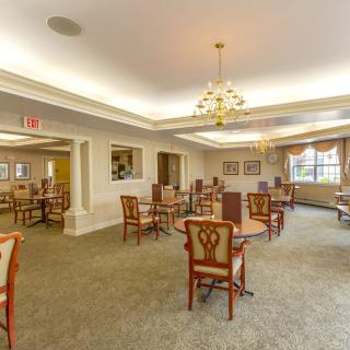 A spacious dining room featuring elegant furniture and a chandelier.