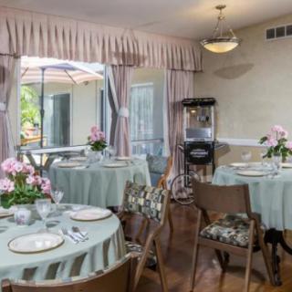 A cozy dining area with tables set for a meal, featuring floral centerpieces and a popcorn machine in the corner.