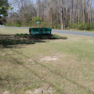 A green sign visible from the roadside, surrounded by grass and trees.
