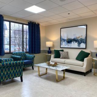 A modern living room with a sofa, patterned chairs, and artwork on the wall.