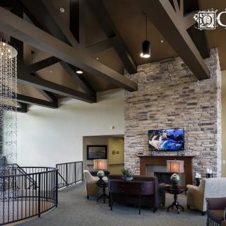 A modern living room with a stone fireplace, exposed wooden beams, and a seating area.