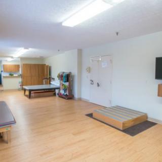 A spacious therapy room equipped with exercise equipment for rehabilitation sessions.