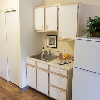 A compact kitchenette featuring a sink, cabinets, and a refrigerator.