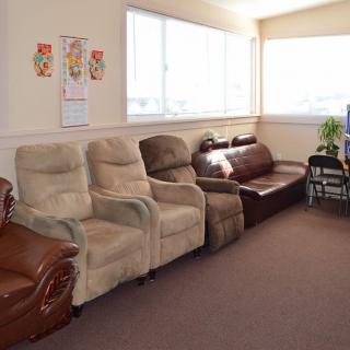 A well-lit waiting room with various seating options including recliners and a sofa.