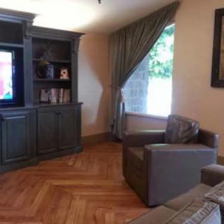 A cozy living room featuring a television, an armchair, and a bookshelf with various items.