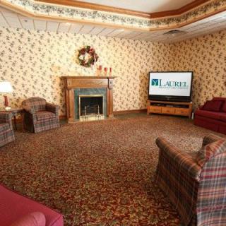 A cozy living room with floral wallpaper, featuring a fireplace, television, and comfortable seating.