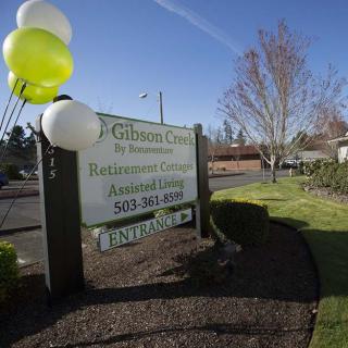 An outdoor sign with balloons advertises a retirement and assisted living community.