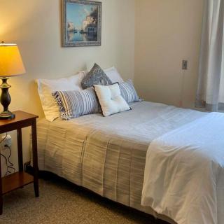 A cozy bedroom with a neatly made bed, decorative pillows, and a bedside lamp.