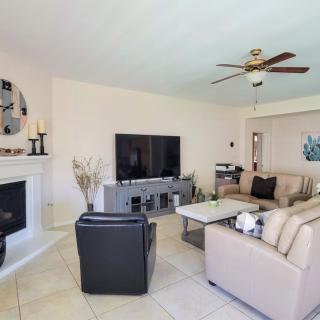 A cozy living room featuring a large television, stylish sofas, and a modern fireplace.