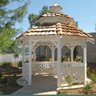 A charming white gazebo with a wooden roof in a garden setting.