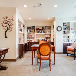 A cozy library room featuring wooden bookshelves, comfortable seating, and elegant decor.