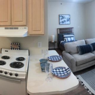 A cozy apartment interior featuring a compact kitchen with an oven and a small living area with a couch and modern decor.