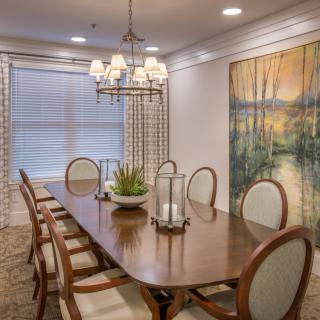 A beautifully designed dining room featuring a large wooden table, elegant chairs, a stylish chandelier, and wall artwork.
