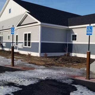A building with designated handicap parking spaces and patches of snow in the parking lot.
