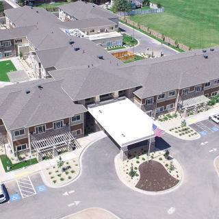 Aerial view of a large building complex with landscaped surroundings and parking areas.