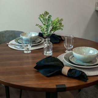 A modern dining table setup with ceramic bowls, elegant place settings, and a touch of greenery.
