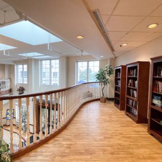 A spacious library interior featuring wooden bookshelves and abundant natural light from skylights.