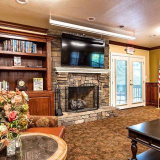 A cozy living room with a stone fireplace, television, and bookshelves.