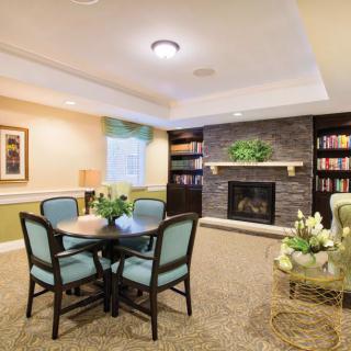 A cozy living room with a fireplace, bookshelves, and a round table surrounded by chairs.