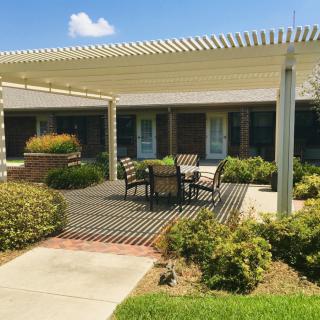 A cozy outdoor patio with a pergola and seating area surrounded by greenery.