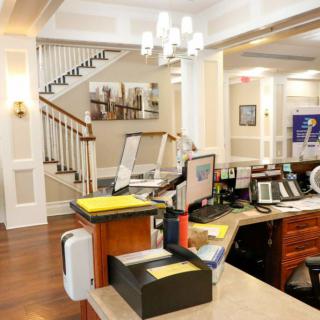 A modern office reception area with a desk, computer equipment, and a staircase in the background.