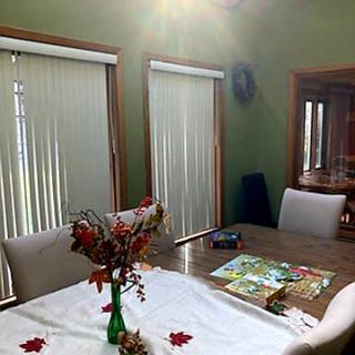 A sunlit dining room with a table decorated with flowers in a vase.