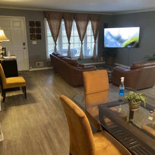 A cozy living room with brown sofas, a mounted television, and a dining area.