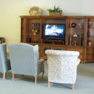 A cozy living room setup with comfortable chairs facing a television on a wooden bookshelf.
