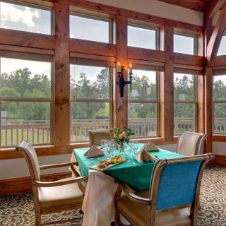 A cozy dining area with a wooden interior and large windows offering a scenic view.