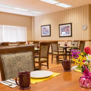 A cozy dining room with neatly arranged tables, chairs, and vibrant floral decorations.