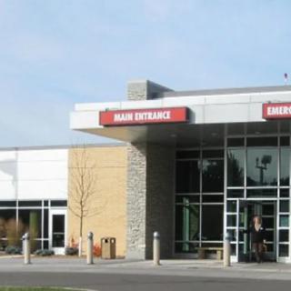 The main entrance of a modern hospital building with glass windows.