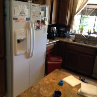 A cozy kitchen with a refrigerator, countertop, and sink by the window.