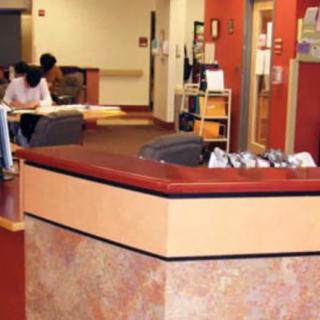 A reception desk in a spacious office lobby with seating and reading materials.