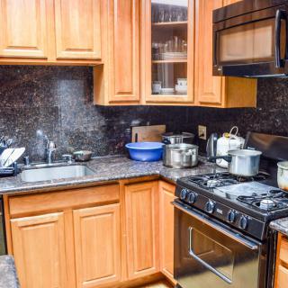A cozy kitchen with wooden cabinets, a stove, microwave, and various appliances on the countertop.