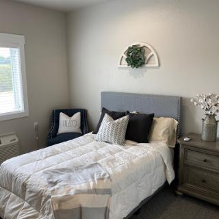 A cozy and modern bedroom featuring a neatly made bed, stylish cushions, and minimalistic decor.