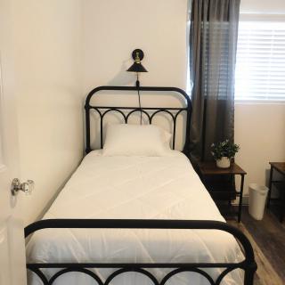 A minimalist bedroom with a single black metal-framed bed and simple decor.